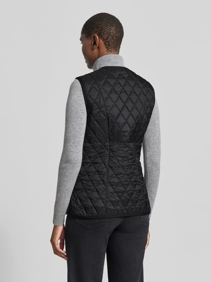 Frauenmodel trägt Regular Fit Weste mit V-Ausschnitt Modell 'BETTY' von Barbour in Schwarz mit Rautensteppung, Damen Weste, Ganzkörperansicht Rückansicht.