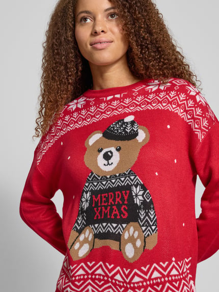 Frauenmodel trägt Regular Fit Strickpullover mit Weihnachtsmotiv Modell 'TEDDY' von Only in Rot mit grafischem Muster und Rundhals, Nahaufnahme Oberkörper.