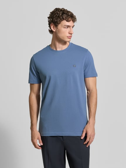 Männermodel trägt T-shirt aus katoen met ronde hals van Christian Berg Men in regular fit, labeldetail, blauwe tint, ruglengte bij maat M 71 cm, Ganzkörperansicht von vorne.