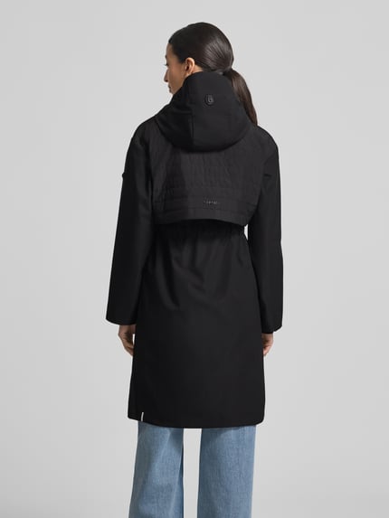Frauenmodel trägt Mantel mit Kapuze und Tunnelzug Modell 'ELSA' von khujo in Schwarz, Regular-Fit, Rückenansicht, glatte Texturen, Rückenlänge bei Größe S: 96 cm, Schulterbreite bei Größe S: 49 cm, Brustweite bei Größe S: 51 cm, Ärmellänge bei Größe S: 60 cm