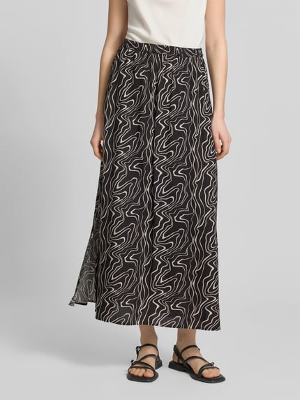 Frauenmodel trägt Ausgestellter Maxi-Rock aus reiner Viskose Modell 'EASY JOY' von Vero Moda mit grafischem Allover-Muster in Schwarz und Weiß, elastischer Bund, Popeline-Optik, Ganzkörperansicht von vorne.