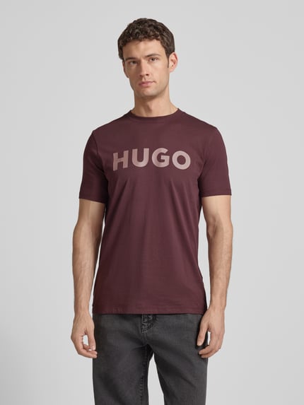 Männermodel trägt Regular Fit T-Shirt aus reiner Baumwolle Modell 'DULIVIO' von HUGO in Optik: Unifarben mit Label-Print, Rundhals, Kurzarm, Ganzkörperansicht von vorne.