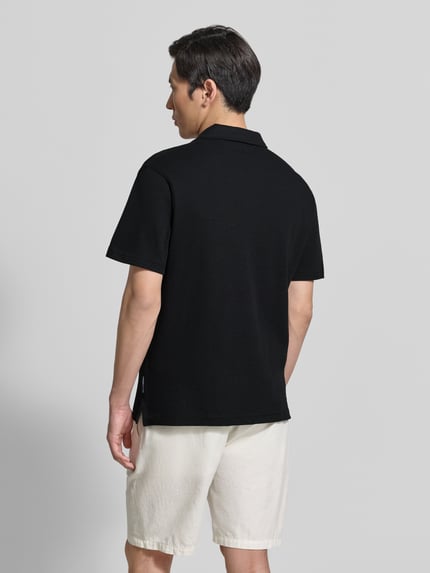 Männermodel trägt Relaxed Fit Poloshirt aus Baumwoll-Mix von Tom Tailor Denim in Schwarz, unifarben, Piqué-Struktur, Ganzkörperansicht Rückansicht.