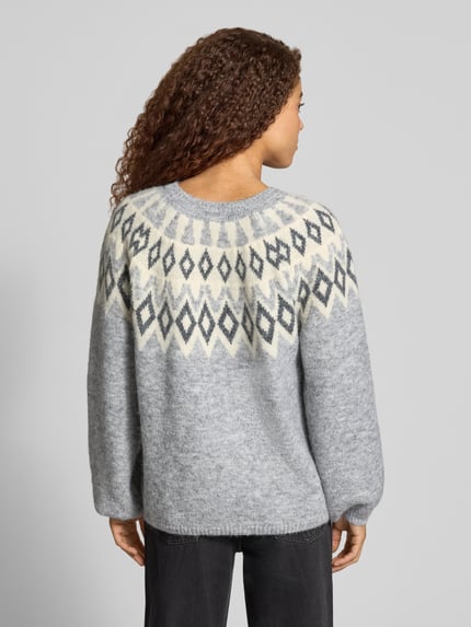 Frauenmodel trägt Pullover mit Jacquardpasse von ONLY, Strickoptik in Grau mit mehrfarbigen Rauten, elastische Bündchen, Ganzkörperansicht Rückansicht.