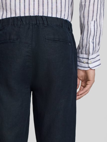 Männermodel trägt Leinenhose mit Eingrifftaschen Modell 'Pandrup' von Casual Friday in Dunkelblau, reine Leinenstruktur, Nahaufnahme Rückansicht, Regular Fit, Bundweite 42 cm, Innenbeinlänge 83 cm.