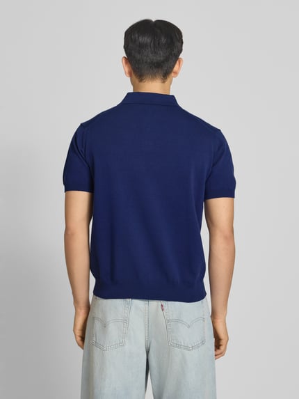 Männermodel trägt Regular Fit poloshirt met labelstitching model 'Speedtrap' van PROHIBITED, puur katoen, donkerblauw, ruglengte maat M 64 cm, ganzkörperansicht rückansicht.