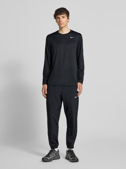 Männermodel trägt Form Pants mit Logo-Print und Eingrifftaschen von NIKE TRAINING in Schwarz, Körpernaher-Schnitt, Ganzkörperansicht von vorne.