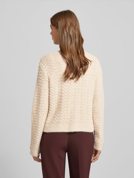 Frauenmodel trägt Strickjacke mit Rundhalsausschnitt und Knopfleiste von More & More, Damen Regular-Fit, Strukturmuster, Ganzkörperansicht Rückansicht.