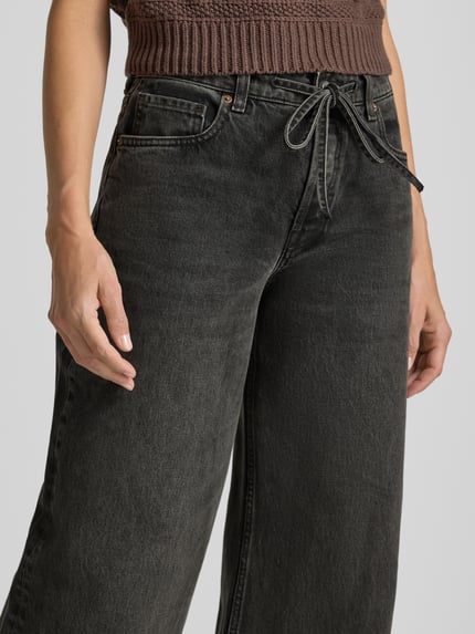 Frauenmodel trägt Wide & Loose Fit Jeans aus reiner Baumwolle Modell 'ASTRAEAAS' von ARMEDANGELS in dunklem Grau, Nahaufnahme Oberkörper, Damen Wide & Loose Fit Jeans von ARMEDANGELS.
