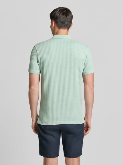 Männermodel trägt Slim Fit Poloshirt mit Logo-Stitching von Lerros aus Baumwoll-Mix in Hellgrün, Rückenlänge 74 cm, Ganzkörperansicht Rückansicht.