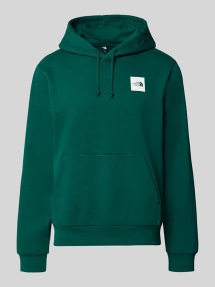 Produktfoto, Regular Fit Hoodie mit Känguru-Tasche von The North Face in Dunkelgrün mit gerippten Abschlüssen und Kapuze mit Tunnelzug, glatte Struktur.