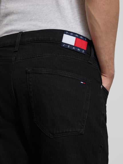 Männermodel trägt zwarte Straight Fit Jeans aus katoenmix Modell 'RYAN' van Tommy Jeans met labelpatch, 5-pocketmodel, detailaufnahme achterzak.