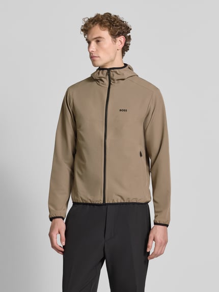 Mężczyzna model nosi Regular Fit Trainingsjacke mit Kapuze Modell 'LW_COMMUTERPRO' von BOSS Green w kolorze beżowym, czarny zamek, gładka tekstura, Ganzkörperansicht von vorne.