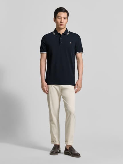 Męski model nosi Regular Fit Poloshirt mit Kontraststreifen od Christian Berg Men z bawełny, krój regular fit, paski w kontrastowym kolorze, listwa guzikowa, długość tyłu w rozmiarze M: 71 cm, całkowity widok z przodu