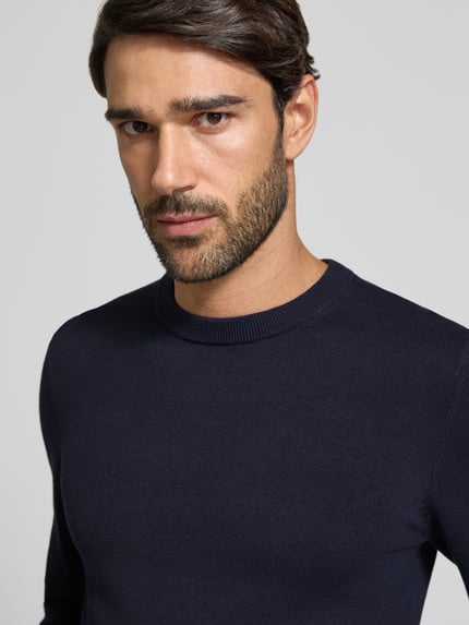 Männermodel trägt Strickpullover aus Baumwoll-Kaschmir-Mix mit Rundhalsausschnitt von MCNEAL, navy, feine Textur, Nahaufnahme Oberkörper. Rückenlänge bei Größe M 70 cm, Ärmellänge 74 cm, Regular Fit.