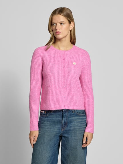 Frauenmodel trägt Cardigan mit Label-Patch von ONLY, unifarben in Pink, Strickoptik, Rundhals, Knopfleiste, Langarm, Nahaufnahme Oberkörper.