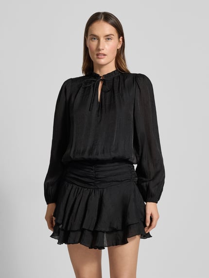 Frauenmodel trägt Cocktailkleid im Stufen-Look Modell 'Bari' von Neo Noir aus schwarzem Chiffon mit Schlüsselloch-Ausschnitt, taillierter Schnitt, Minikleid, strukturierte Oberfläche, Ganzkörperansicht von vorne.