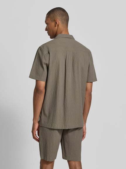 Männermodel trägt Modern Fit Freizeithemd mit Brusttaschen von Lindbergh, Baumwoll-Mix mit Stretch-Anteil, Strukturmuster, Reverskragen, Knopfleiste, Rückenlänge 77 cm, Schulterbreite 49 cm, Ärmellänge 27 cm, Farbe Oliv, lockerer Schnitt, Ganzkörperansicht Rückansicht.