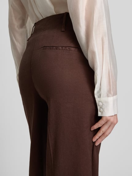 Frauenmodel trägt Straight Fit Leinenhose mit Viskose-Anteil von Stefanel, braun, glatte Textur, mit Bügelfalten und Eingrifftaschen, Nahaufnahme Rückansicht.
