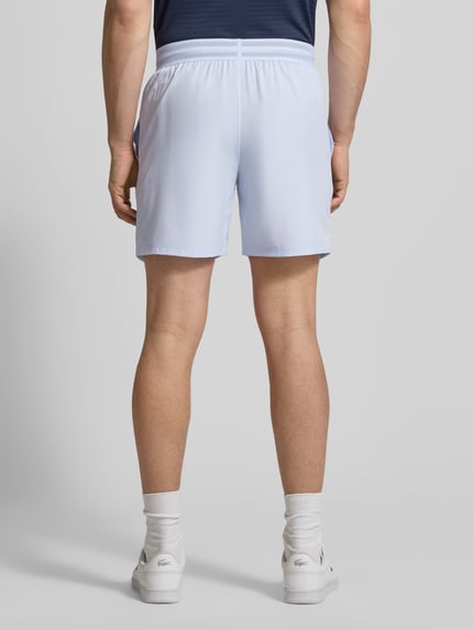 Männermodel trägt Loose Fit Sport-Shorts mit Mesh-Bund von Lacoste Sport in Unifarbe mit Logo-Stitching, Rückansicht Ganzkörperansicht.