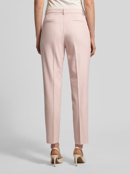 Frauenmodel trägt Hose mit Bügelfalten und Eingrifftaschen von More & More in zartem Rosa, Material-Mix mit Viskose-Anteil, Slim-Fit, Gesäßtaschen, Ganzkörperansicht Rückansicht.