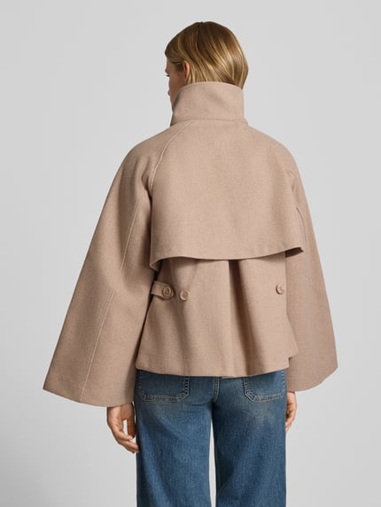 Frauenmodel trägt Jacke mit Stehkragen und Kimonoärmeln von Gina Tricot in Beige, strukturierte Oberfläche, Ganzkörperansicht Rückansicht. Rückenlänge, Schulterbreite, Brustweite und Ärmellänge bei Größe S angegeben.