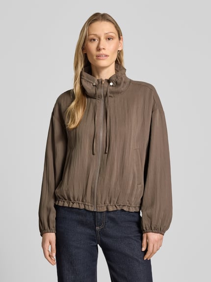 Frauenmodel trägt Regular Fit Jacke aus Lyocell-Mix mit Viskose-Anteil von Fynch-Hatton in Braun mit Stehkragen, Reißverschluss, elastischen Abschlüssen, glatter Struktur, Ganzkörperansicht von vorne.