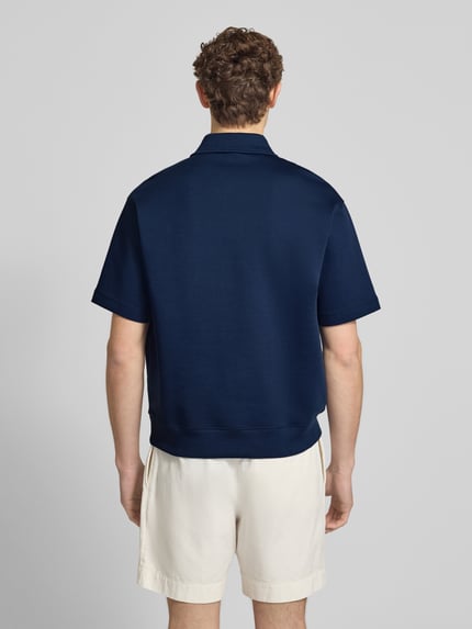 Männermodel trägt Loose Fit Poloshirt mit Label-Stitching von ARMANI EXCHANGE aus Baumwoll-Mix mit Stretch-Anteil, Ganzkörperansicht Rückansicht.