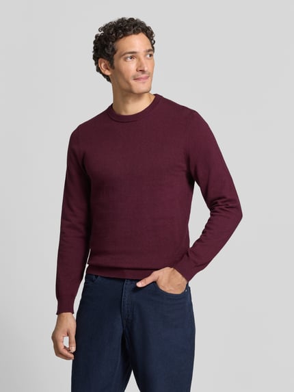 Männermodel trägt Strickpullover aus Baumwoll-Kaschmir-Mix mit Rundhalsausschnitt von MCNEAL, burgunderrot, Regular Fit, Ganzkörperansicht von vorne. Rückenlänge 70 cm, Ärmellänge 74 cm.