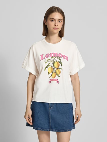 Frauenmodel trägt Boxy Fit T-Shirt aus reiner Baumwolle Modell 'MINNA' von Only, unifarben mit Motiv-Print, Ganzkörperansicht von vorne.