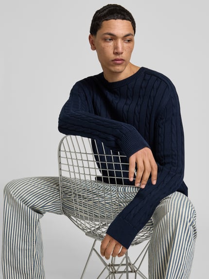 Męski model nosi Slim Fit Pullover in Strick-Optik od Filippa K, granatowa bawełna, krój slim fit, okrągły dekolt, elastyczne wykończenia, długość tyłu w rozmiarze M: 69 cm, widok na górną połowę ciała z przodu