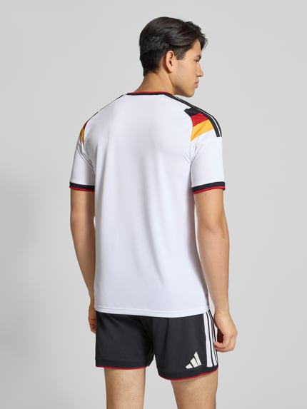 Männermodel trägt DFB Heimtrikot mit Label-Print von adidas Sportswear, weiß mit schwarzen und bunten Details, Regular-Fit, Rückenlänge in Größe M 73 cm, gerippte Ärmelabschlüsse, Ganzkörperansicht Rückansicht.
