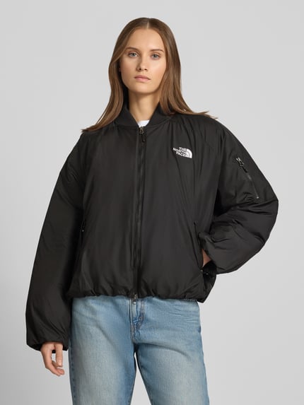 Frauenmodel trägt Bomberjacke mit Label-Stitching Modell 'CHOQA' von The North Face, schwarz, glatte Textur, Ganzkörperansicht von vorne. Relaxed Fit, Stehkragen, Zweiwege-Reißverschluss, Reißverschlusstaschen, Rückenlänge 60 cm, Schulterbreite 52 cm, Brustweite 65 cm, Ärmellänge 48 cm.