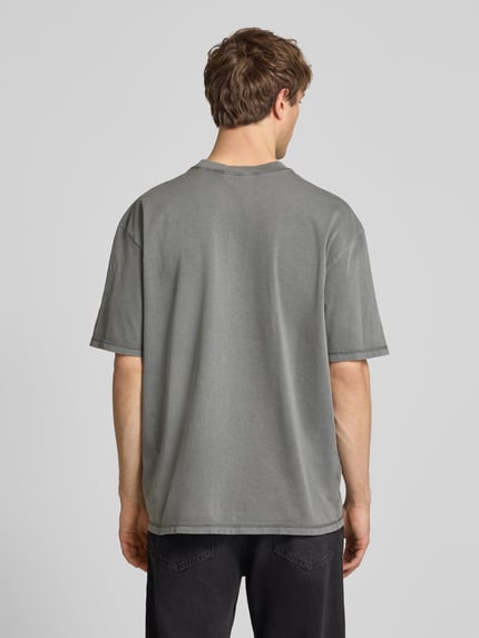 Männermodel trägt Oversized Fit T-Shirt mit Logo-Stitching von Pegador in Grau, Reine Baumwolle, Rundhalsausschnitt, Herren T-Shirt, Ganzkörperansicht Rückansicht. Rückenlänge bei Größe M: 71 cm.
