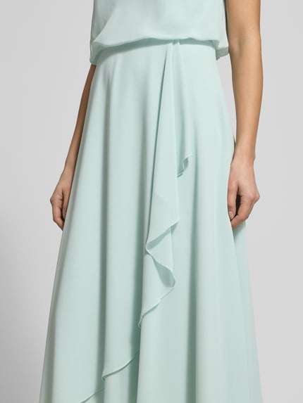 Vrouwenmodel draagt knielanges cocktailjurk met waterfall-ausschnitt van Christian Berg Cocktail van chiffon in mint, getailleerd model, brede bandjes, wikkellook, ritssluiting achter, ruglengte maat 36: 120 cm, borstwijdte maat 36: 45 cm. Detailopname.