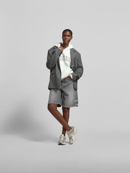Vrouwenmodel draagt Oversized Hoodie mit Logo-Stitching van Anine Bing in wit, katoen, oversized fit, met logo-stitching, capuchon en kangoeroezak, ruglengte maat S 64 cm, volledige lichaamsaanzicht van voren.