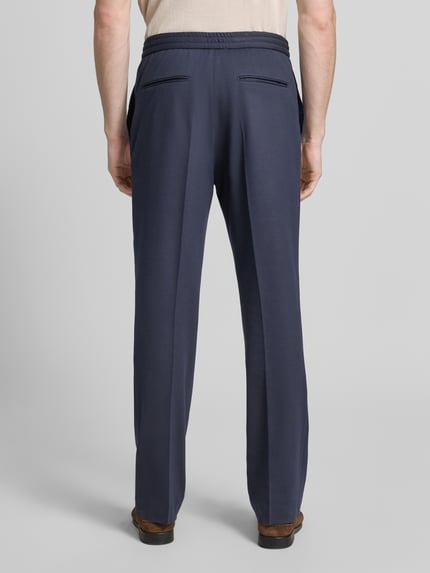 Männermodel trägt Regular Fit Stoffhose aus Viskose-Mix Modell 'ISCOVE' von Tiger Of Sweden, navy, Bundfalten, Rückansicht, Ganzkörperansicht Rückansicht. Herren Stoffhose mit Tunnelzug, Bundweite bei Größe 50: 42 cm, Innenbeinlänge: 82 cm.