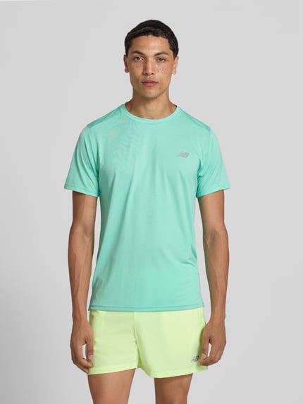Männermodel trägt Funktionsshirt mit Rundhalsausschnitt und Logo von New Balance in Mintgrün, Regular Fit, Ganzkörperansicht von vorne.