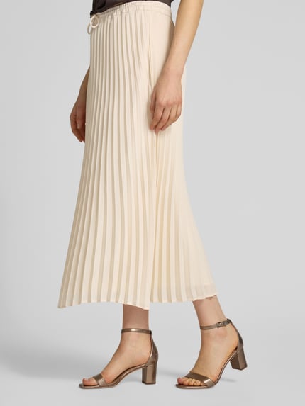Vrouwenmodel draagt Midirock mit Plisseefalten van comma in A-lijn, elastische tailleband met strik, crèmekleur, midi lengte, detailopname linkerzij.