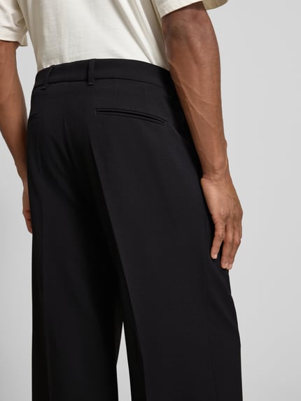 Männermodel trägt Wide Fit Hose mit Bügelfalten Modell 'Leek' von Drykorn, Material-Mix mit Viskose-Anteil, Detailaufnahme Rückansicht