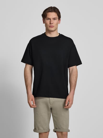 Männermodel trägt T-Shirt mit Rundhalsausschnitt Modell 'BARRON' von Jack & Jones in Schwarz, Regular Fit, Baumwoll-Mix mit Stretch, Ganzkörperansicht von vorne.