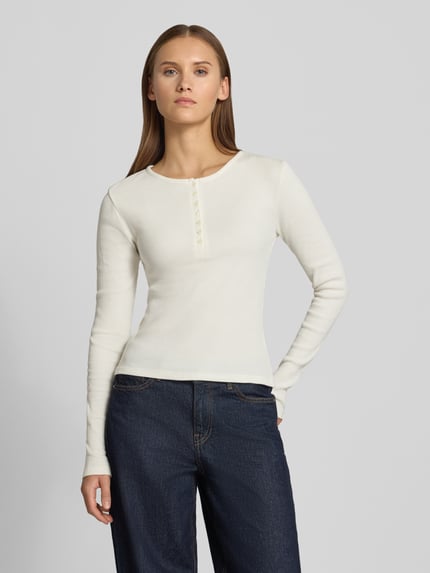Frauenmodel trägt Slim Fit Langarmshirt aus reiner Baumwolle von REVIEW in Offwhite, Feinstruktur, Rundhalsausschnitt, Ganzkörperansicht von vorne.