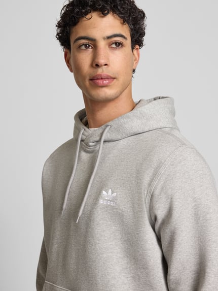 Männermodel trägt Hoodie mit Kapuze von adidas Originals in Grau, Baumwoll-Mix, Label-Stitching, Lockerer-Schnitt, Nahaufnahme Oberkörper.