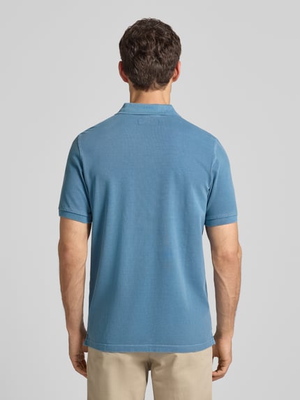 Männermodel trägt Poloshirt aus Baumwolle von MARC O’POLO DENIM in Blau mit Piqué-Struktur, gerader Schnitt, Ganzkörperansicht Rückansicht.