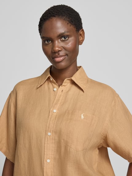 Frauenmodel trägt Oversized Hemdbluse aus reinem Leinen von Polo Ralph Lauren in Unifarbe mit Logo-Stitching, Nahaufnahme Oberkörper.