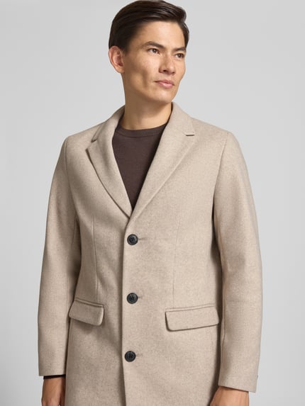 Männermodel trägt Mantel mit Reverskragen und Pattentaschen von Lindbergh, Beige, glatte Struktur, Slim Fit, Nahaufnahme Oberkörper.