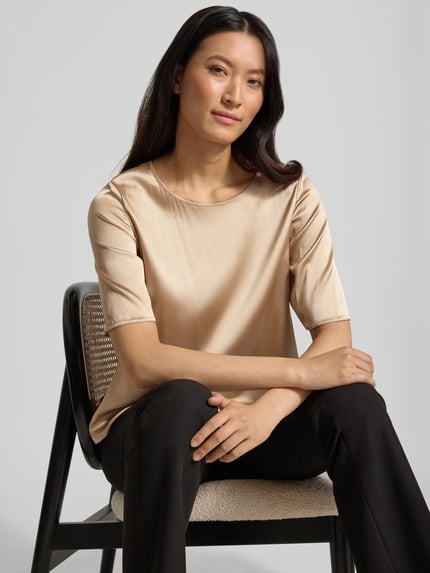 Vrouwenmodel draagt Regular Fit Blusenshirt uit zijde-mix model 'LASTI' van MM by Max Mara in satijn, beige, ronde hals, halflange mouw, zijdezachte textuur, vooraanzicht bovenlichaam, context: dames Blusenshirt, zijde-elastaan-mix, ruglengte 53 cm, mouwlengte 31 cm.