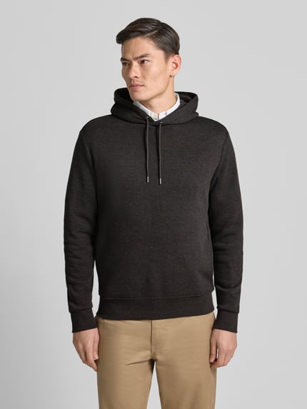 Męski model nosi Hoodie mit Kapuze od Polo Ralph Lauren, bawełniany melanż, luźny krój, ściągacze, widok całej sylwetki z przodu.