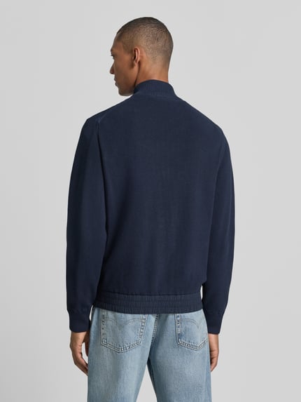 Männermodel trägt Regular Fit Strickjacke aus Baumwoll-Mix Modell 'Kobello' von BOSS, dunkelblau, grob gestrickt, BOSS Orange, Ganzkörperansicht Rückansicht.