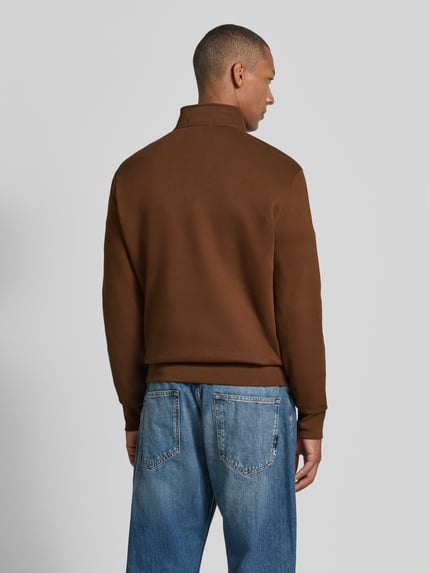 Männermodel trägt Relaxed Fit Troyer aus Baumwoll-Mix von Polo Ralph Lauren in Braun zu blauen Jeans, Ganzkörperansicht Rückansicht. Herren Troyer